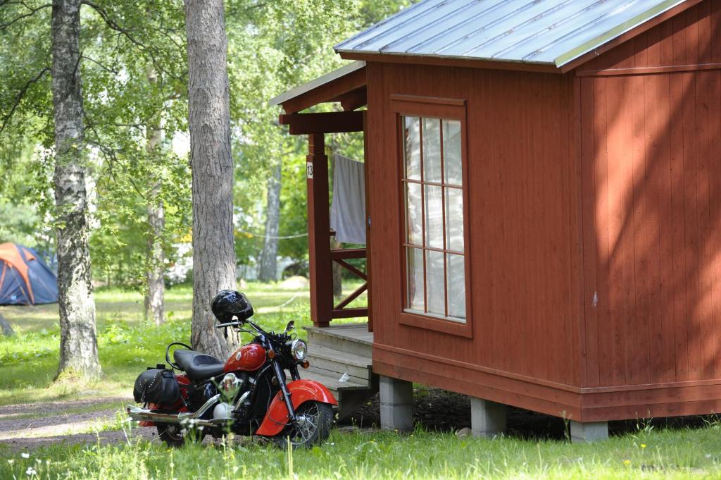 Una motocicleta roja estacionada frente a una casa pequeña en Gröna Uddens Camping, en Mariehamn