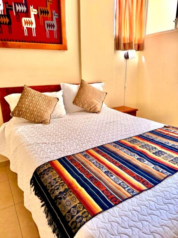 a bed with a colorful blanket on top of it at Tourist House Suites Otavalo in Otavalo