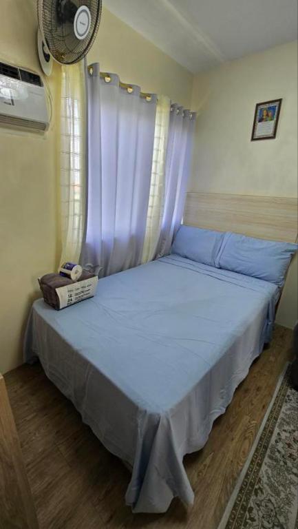 a bedroom with a blue bed with a window at The Cozy Place Stanford 2 in Silang