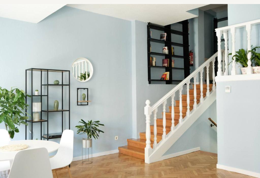 a living room with blue walls and stairs with a white stair case at BaruHaus GRUPOS Rua Legio in León