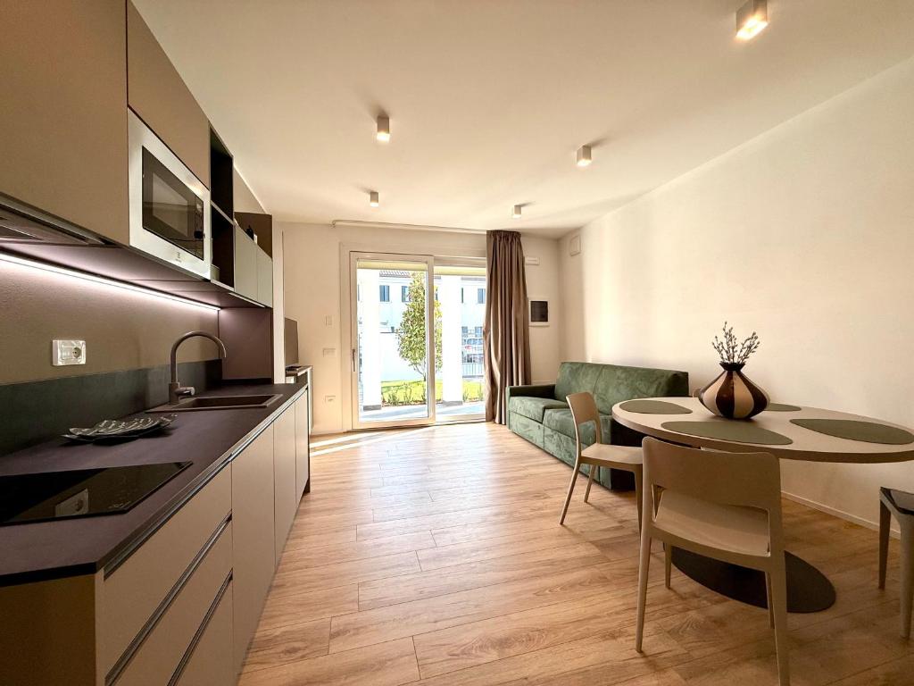 a kitchen and living room with a table and a dining room at LA TERRAZZA APARTMENTS - Sand & Green Apartments - DeltadelPo in Porto Viro