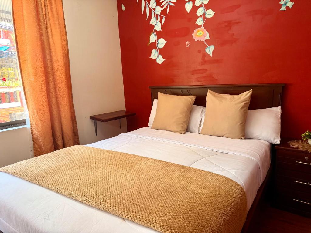 a bedroom with a bed with a red wall at Hostal Green Garden en el centro de Baños de Agua Santa in Baños