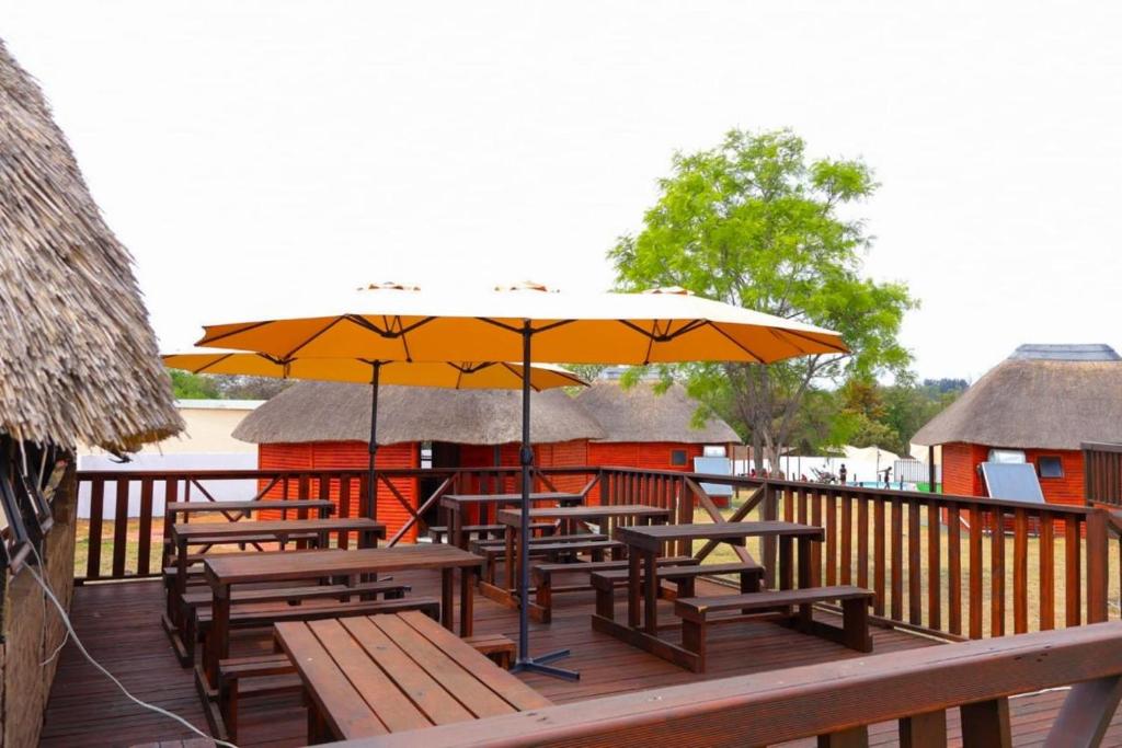 a deck with picnic tables and an umbrella at Oluhle Resort in Hammanskraal