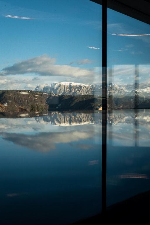 a view of the snow covered mountains through a window at Luis & die Buabm - Gasthof Jenesien in San Genesio Atesino