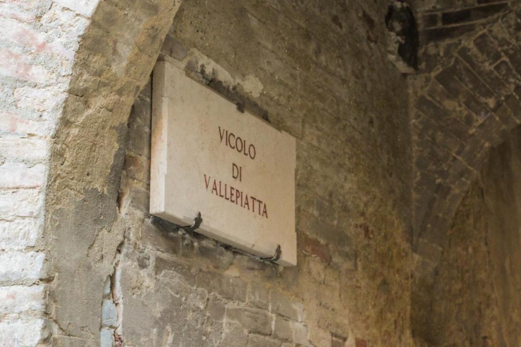 a sign on the side of a brick wall at Il pozzo & La volta in Siena