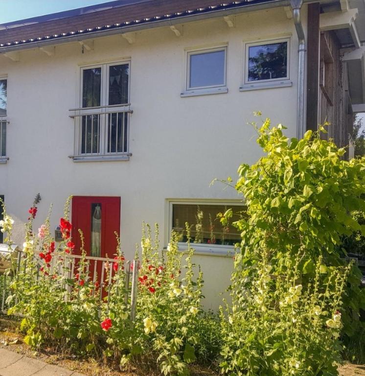 a white house with a red door and some bushes at Sonniges Sundchalet in Stralsund