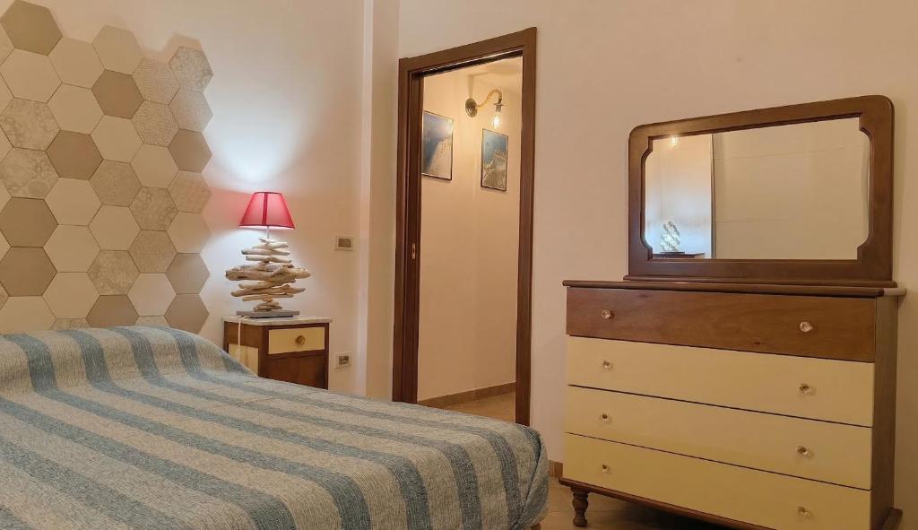 a bedroom with a bed and a dresser with a mirror at CRema Beach in Palmi