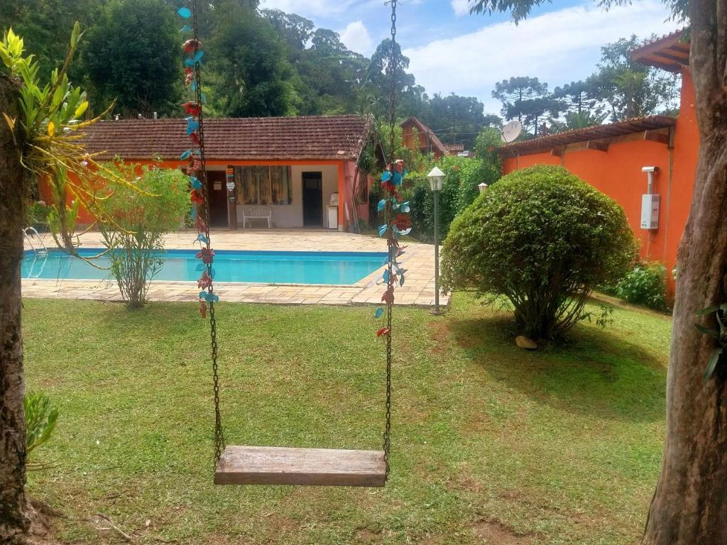 a swing in a yard in front of a house at Chalé Bosque Encantado Maringá MG in Itatiaia