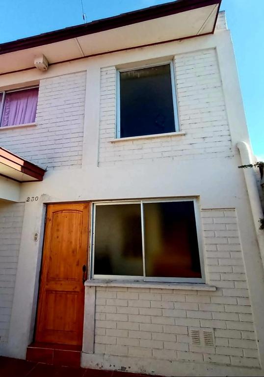 a house with a wooden door and two windows at Alojamiento La Serena CQ in La Serena