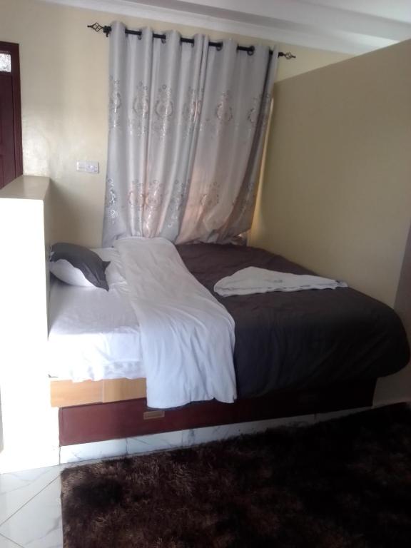 a bedroom with a bed with a window with a curtain at Wasini gardens,, vingazini in Mtwapa