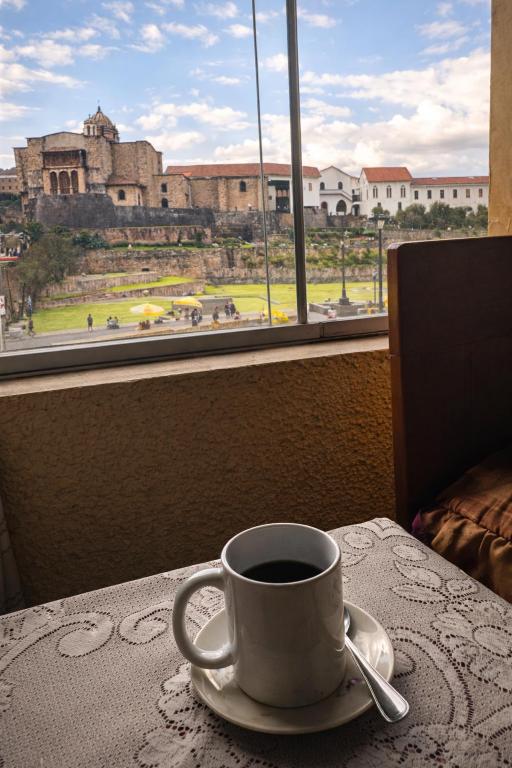 a cup of coffee sitting on a table in front of a window at Hostal Santo Domingo in Cusco