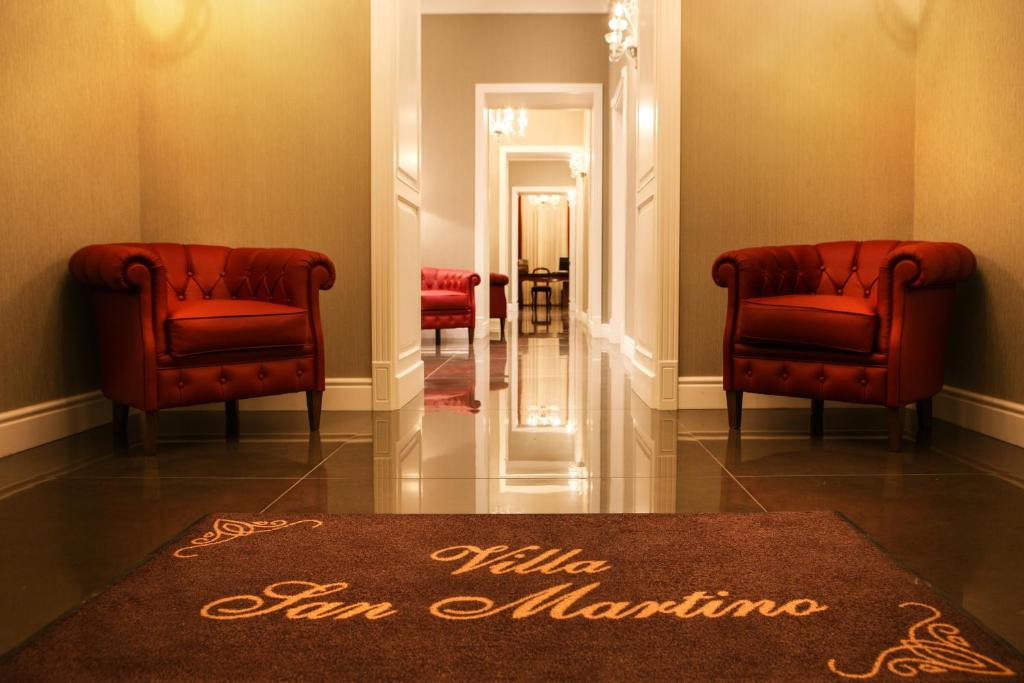 un corridoio con due sedie rosse e un tappeto di Villa San Martino a Napoli
