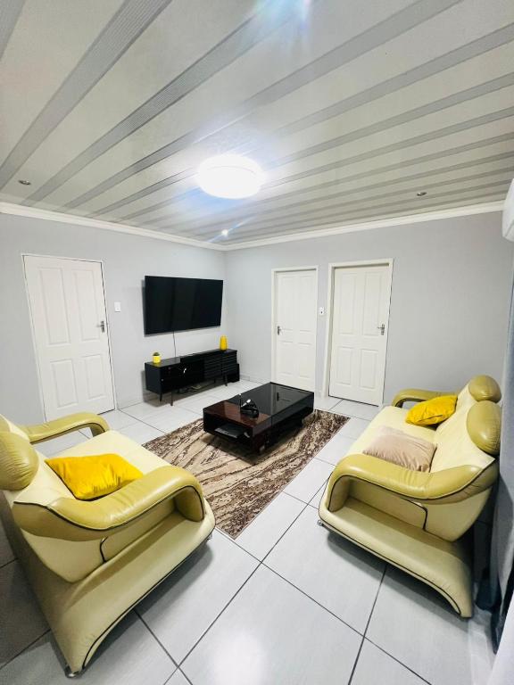 a living room with two chairs and a flat screen tv at Modern Comfort, Easy Access Everywhere in Vanderbijlpark