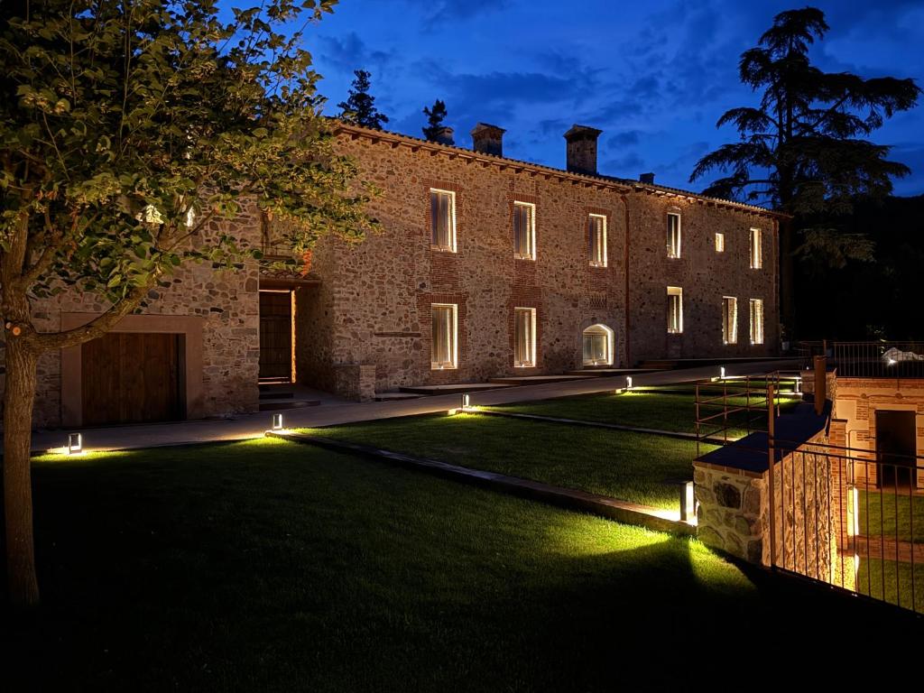 a large brick building with lights on the lawn at Masia de Can Roig in Riells