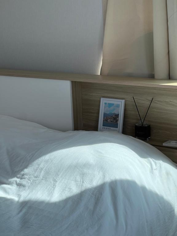 a bedroom with a white bed with a wooden headboard at Stay Mokpo,2R1B,목포역,케이블카,동부시장,최대4인 in Mokpo