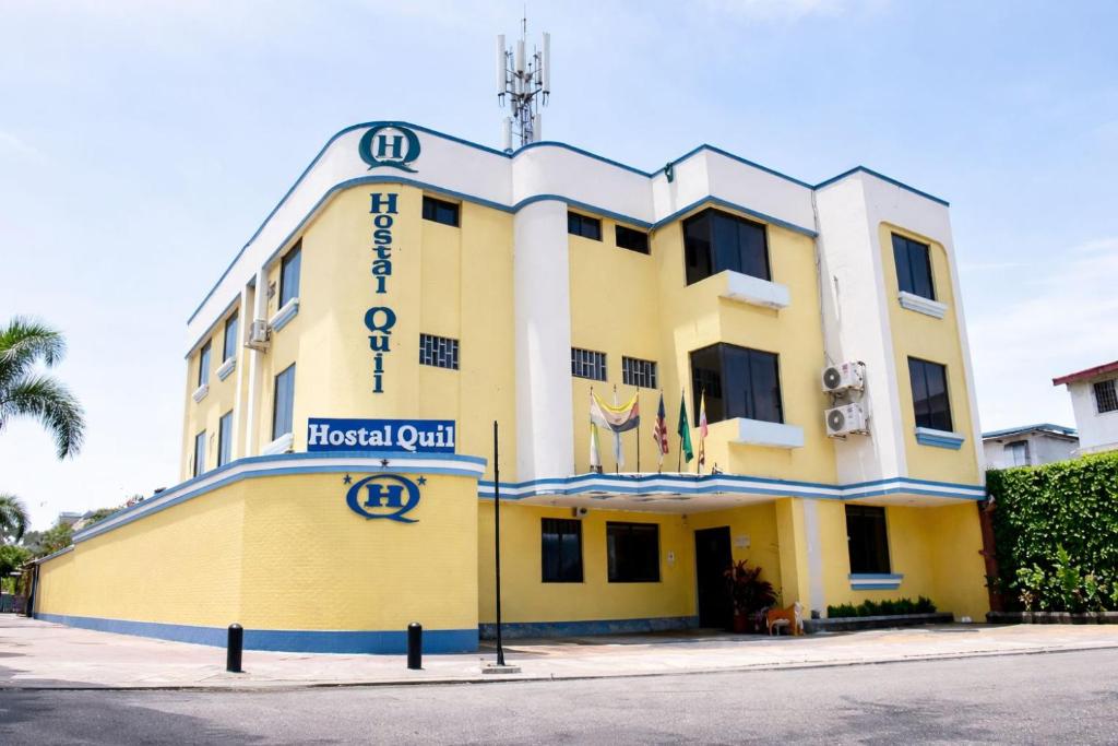 ein gelb-weißes Gebäude mit einem Schild darauf in der Unterkunft Hostal Quil in Guayaquil