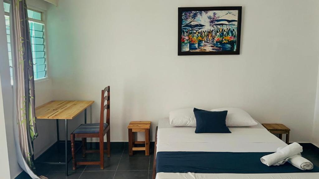 a room with a bed and a table and a desk at La Petite Maison in Antsiranana