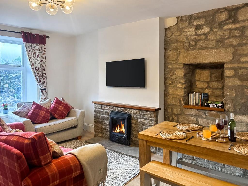 a living room with a fireplace and a tv at Croft House Cottage in Hebden