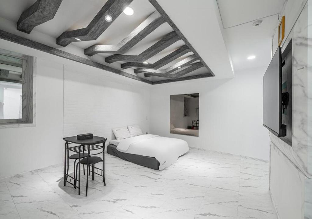 a white bedroom with a bed and a table at Gunsan Hasen Hotel in Gunsan-si