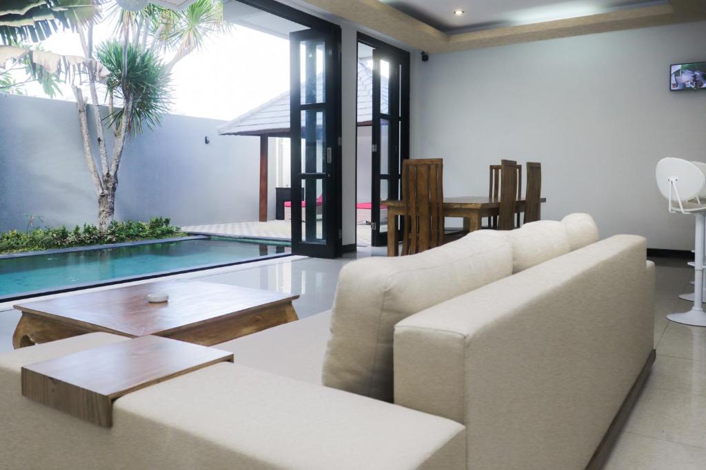 a living room with a couch and a glass table at The Lavana Dzawani Villa Berawa Kuta Bali 3 Bedroom Villa in Canggu