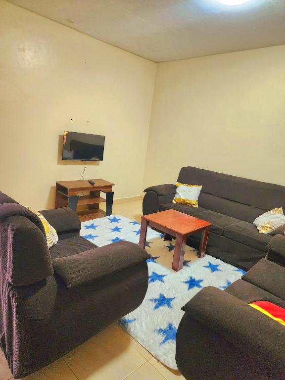 a living room with two couches and a table at Arifa Homes in Ruringʼu