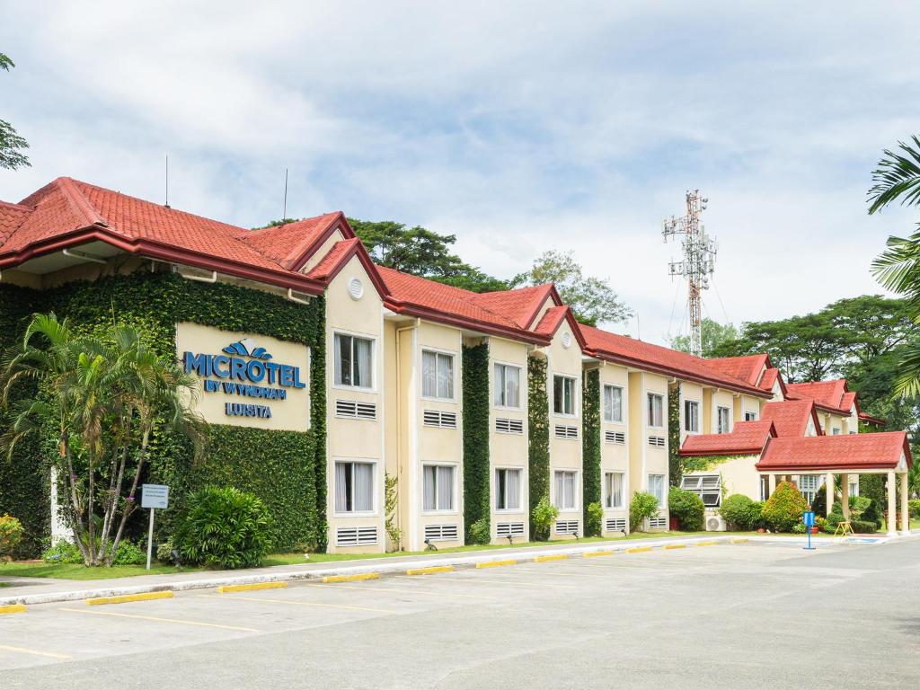 ein großes Gebäude mit rotem Dach in der Unterkunft Microtel by Wyndham Tarlac in Tarlac City