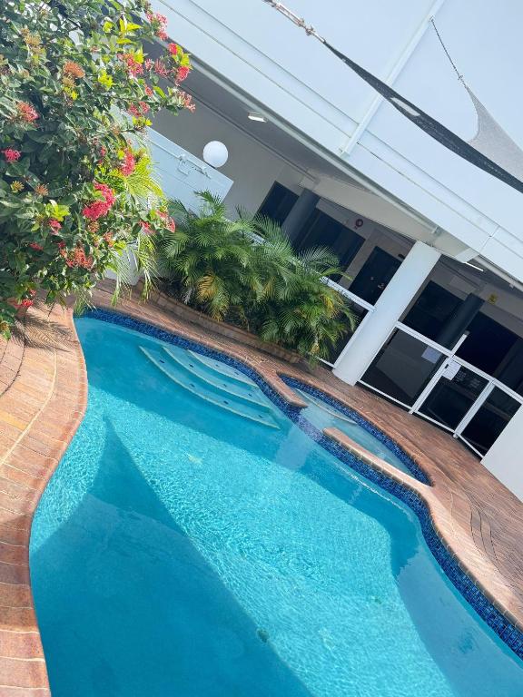 a swimming pool in front of a house with flowers at Centrepoint Motor Inn in Rockhampton