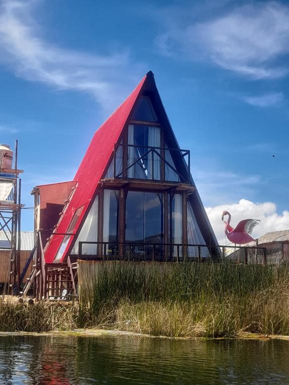 a house with a red roof next to a body of water at Suma Kusi en el Titicaca in Puno