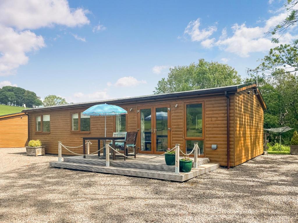 a wooden cabin with a table and an umbrella at Ridge View Lodge - Uk49924 in Dumfries