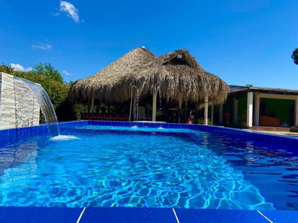 a swimming pool with a straw umbrella and a water fountain at Finca # 20 - Arjona in Turbaco