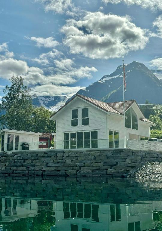 a house with a stone wall next to a body of water at Newly Built Cabin With Sauna By Oldevatnet in Olden