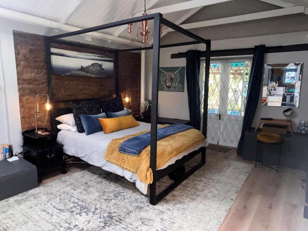 a bedroom with a canopy bed with blue and orange pillows at 1 Queen Vic in Darling