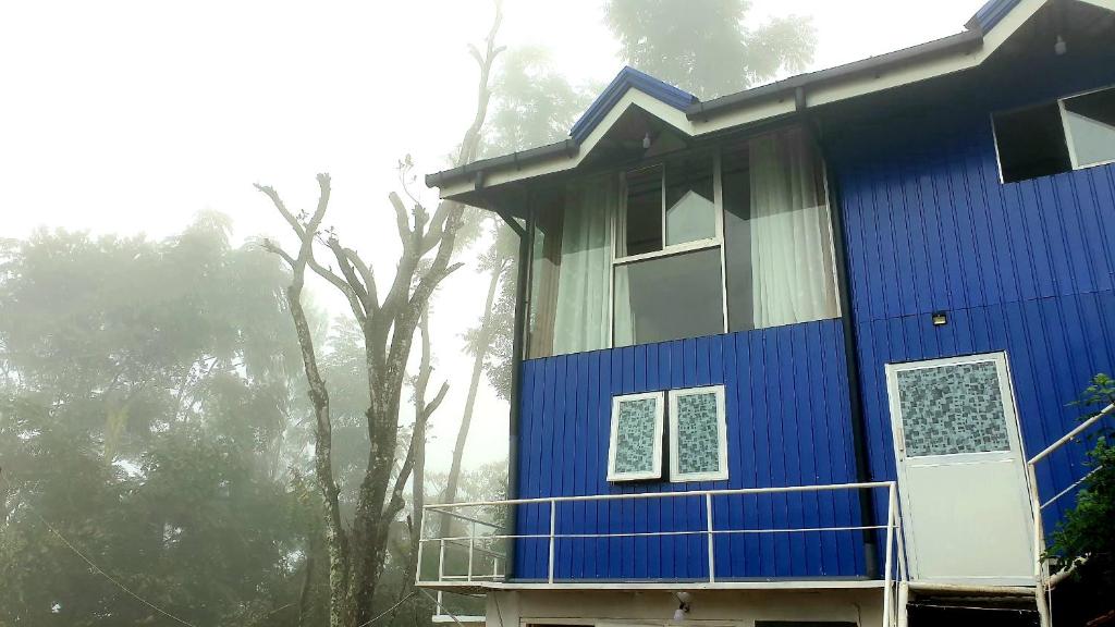 a blue house with a tree in front of it at Kithul Cottage 2 in Watagoda