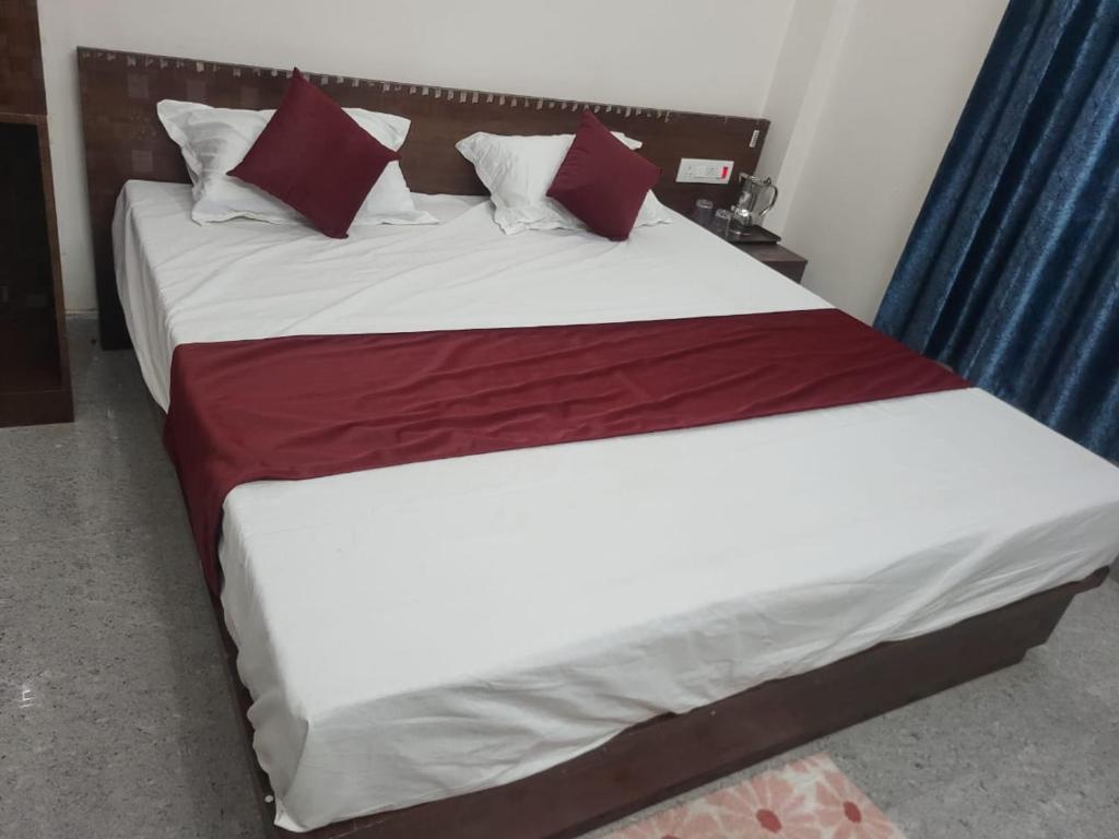 a bedroom with two beds with red and white pillows at Hotel Kunj Palace in Habibnagar