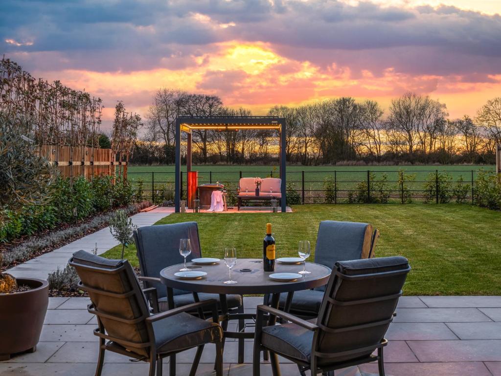 a table with chairs and a bottle of wine on a patio at Uk47692 - Wiggles Cottage in Wimbish