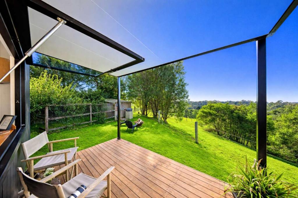 a deck with chairs and a view of a yard at Lily Pad Tiny Home in Maleny