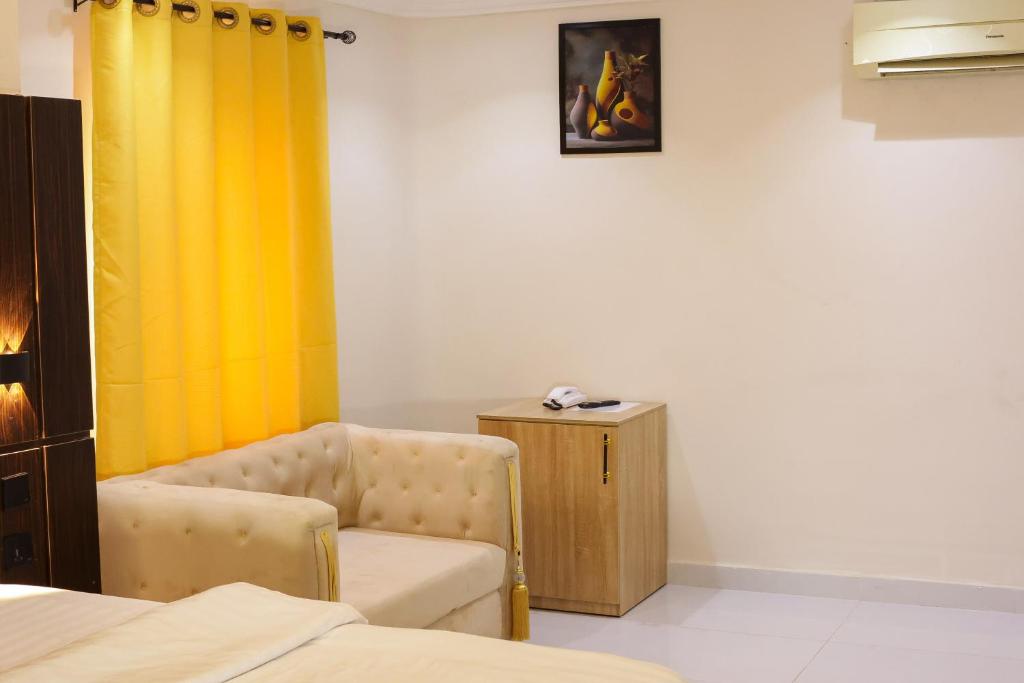 a room with a chair and a yellow curtain at Oasis hotel and suites in Lagos
