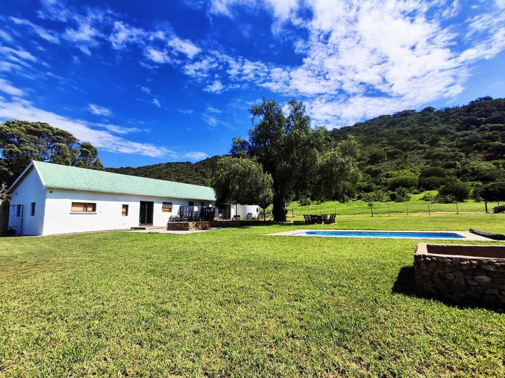 a white house with a yard and a swimming pool at SoetHoek Farm Retreat in Alexandria
