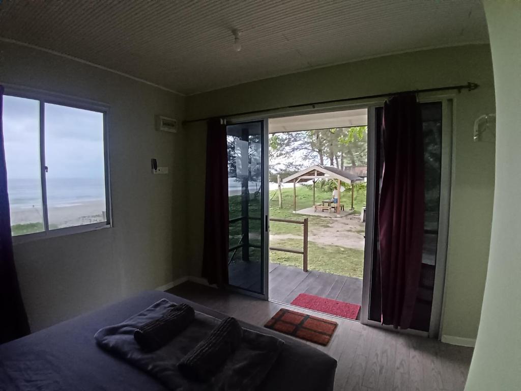 a bedroom with a bed and a large sliding glass door at Sunset Beach House in Kudat