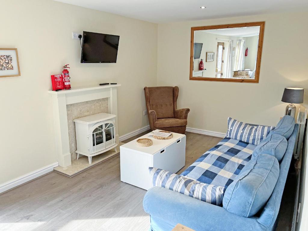 a living room with a blue couch and a chair at Elder Cottage - Uk51371 in Winston