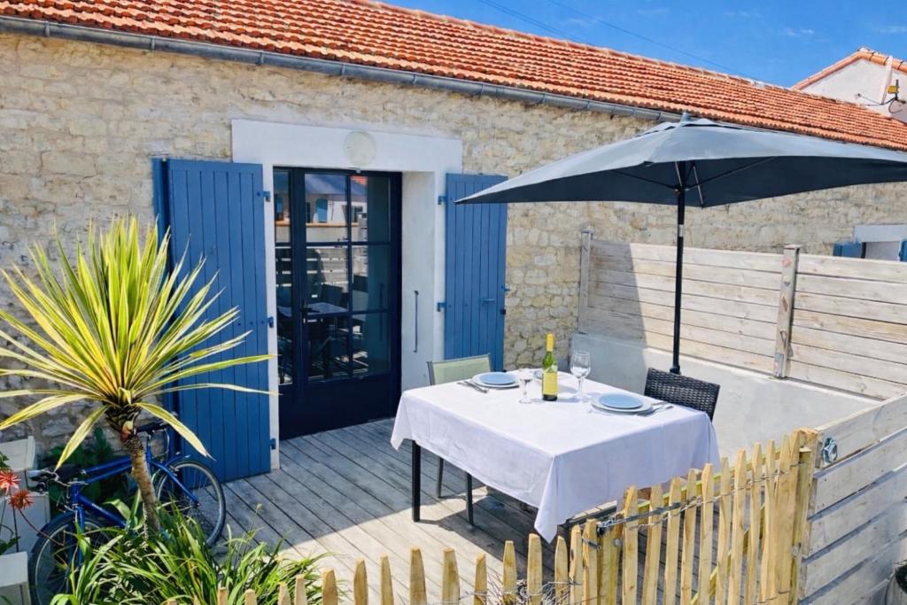 a table with an umbrella on a patio at Residence Clos des Aigrettes -Appartements a 30m du Port de La Cotiniere , Ile d Oleron -commerces et plages a pied in La Cotinière