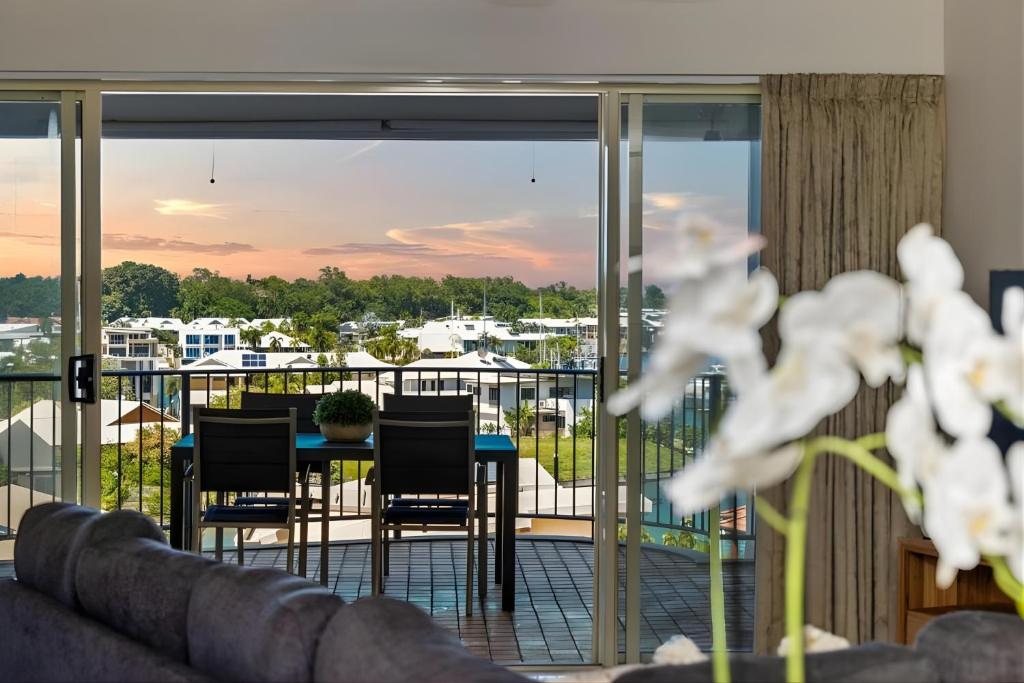 a room with a balcony with a table and chairs at Sunset Stunner Marina Views in Larrakeyah
