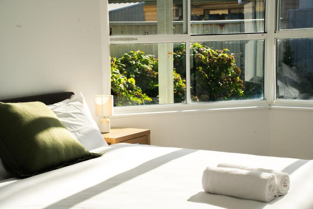 a white bed in a room with a window at The Beachside Gathering in Anna Bay