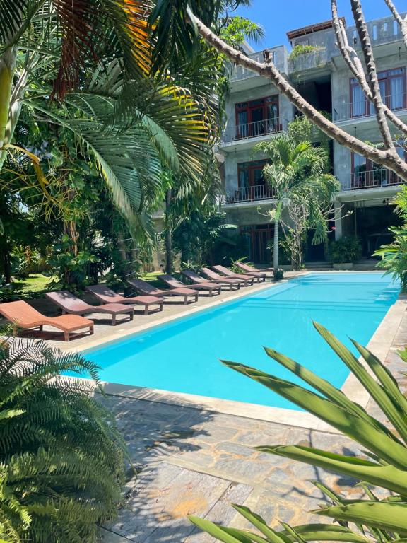 a hotel swimming pool with lounge chairs and palm trees at Surf Gangs Arugambay in Arugam Bay