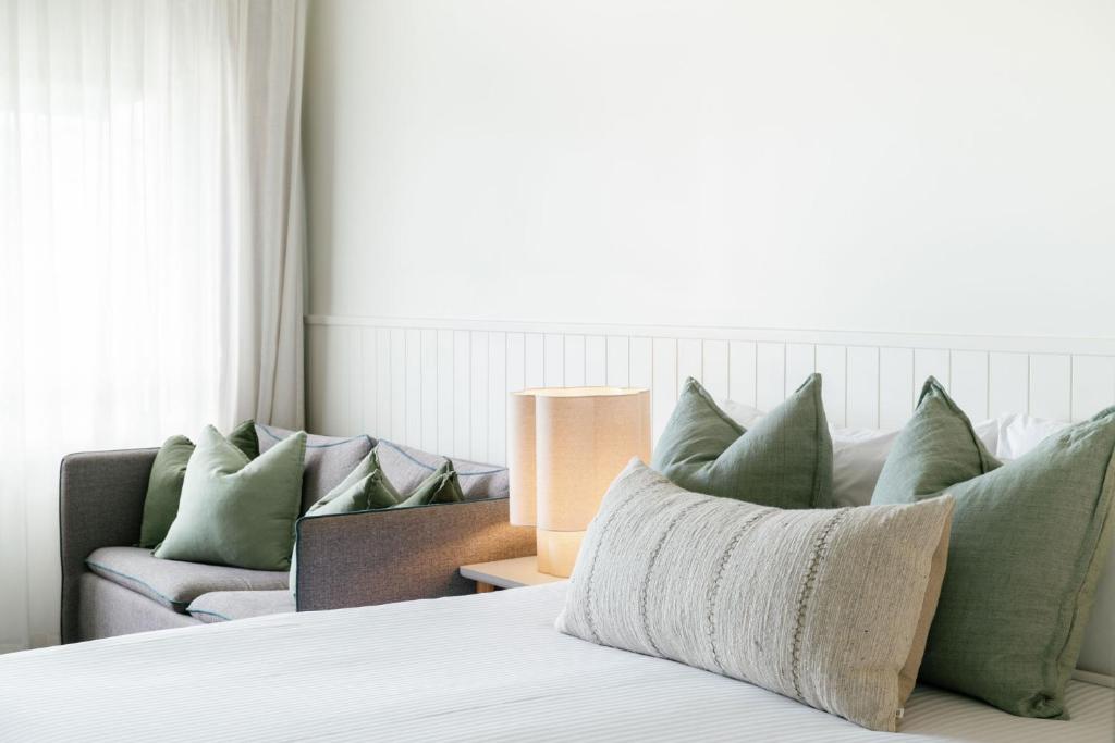 a bedroom with a bed with green pillows and a couch at The Leea, Darwin in Darwin