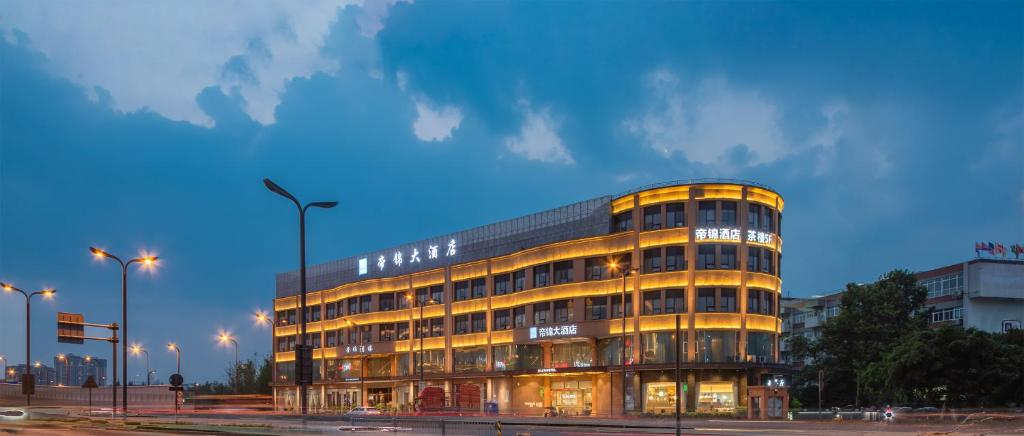 a tall yellow building with lights on at 帝锦大酒店 in Supoqiao