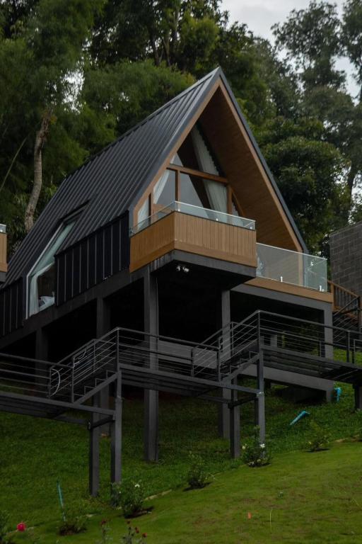 a house with a gambrel roof with a deck at BaanTataChiangmai in Ban Pong Khai Tai