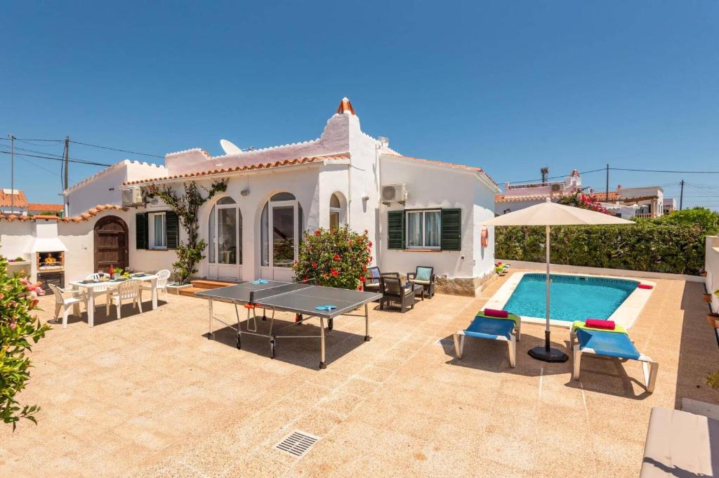 a house with a pool and a table and chairs at Villa Pearla by Villa Plus in Cala en Porter