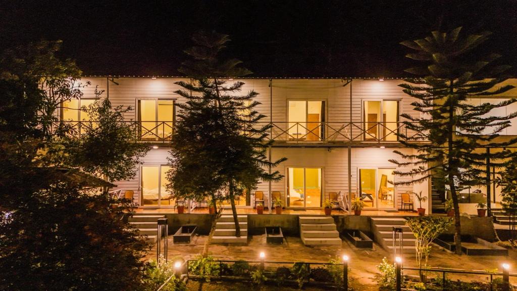 a large white building with a courtyard at night at Aspen Riverside Resort in Rishīkesh