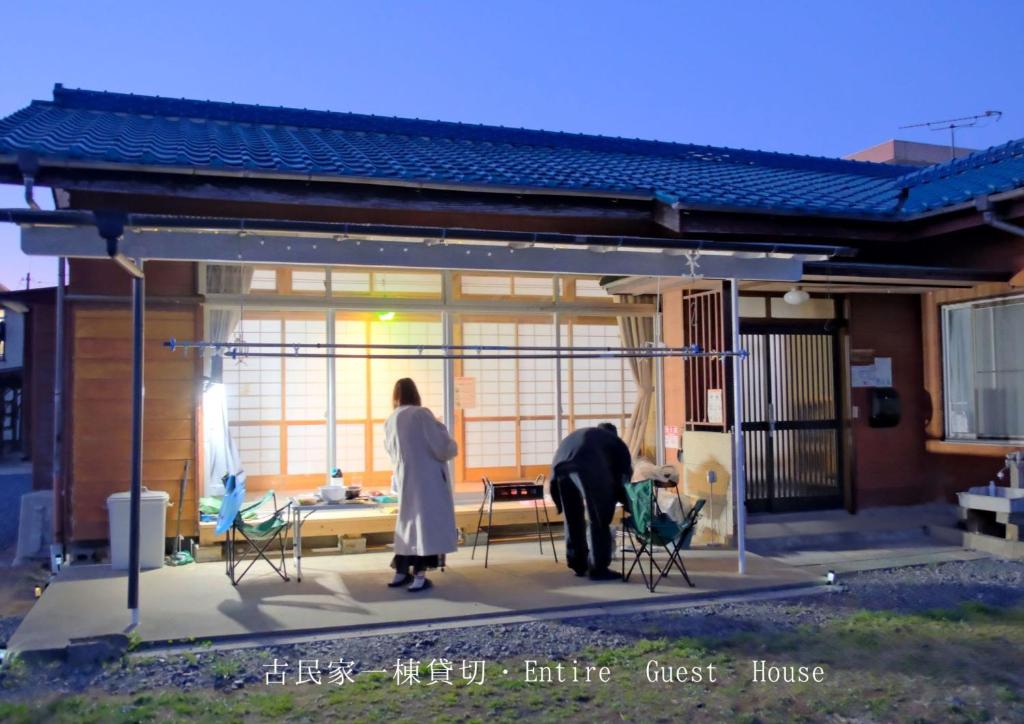 two people standing on a patio of a house at 古民家宿Tabi湊 in Hitachinaka